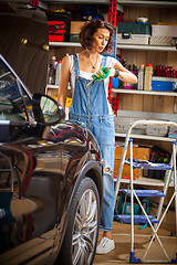Image showing woman mechanic in blue overalls looks at wristwatch