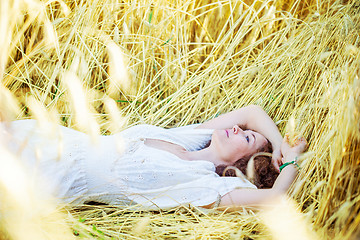 Image showing woman in white dress lies in a field among ears of corn