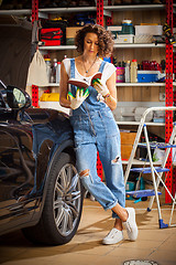 Image showing car mechanic, a beautiful woman studying the instructions for re