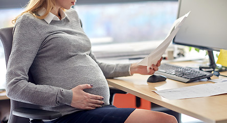 Image showing pregnant businesswoman reading papers at office