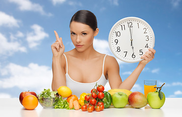 Image showing woman with food and big clock sitting at table