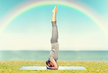 Image showing woman making yoga in headstand pose on mat