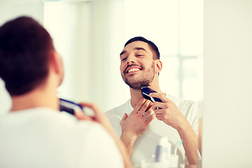 Image showing man shaving beard with trimmer at bathroom