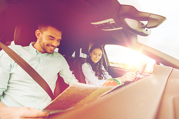 Image showing happy man and woman with road map driving in car