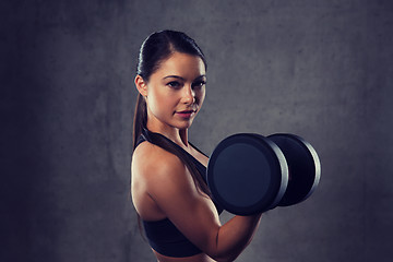 Image showing young woman flexing muscles with dumbbells in gym