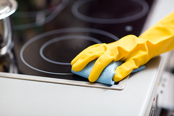 Image showing hand with rag cleaning cooker at home kitchen