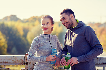 Image showing smiling couple with bottles of water outdoors