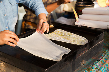 Image showing woman cooking roti pancakes at street market