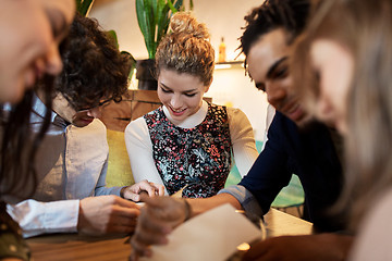 Image showing happy friends looking to menu at restaurant