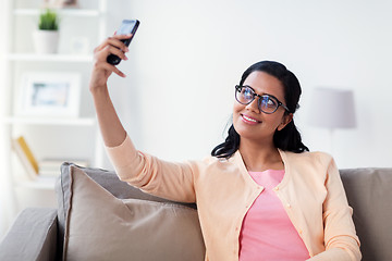 Image showing happy woman taking selfie with smartphone at home