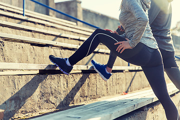 Image showing close up of couple stretching leg on stadium