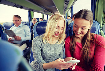 Image showing happy young women in travel bus with smartphone