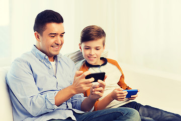 Image showing happy father and son with smartphones at home