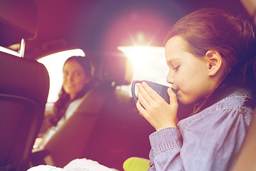 Image showing little girl driving in car and drinking from cup