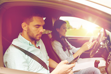 Image showing man and woman with smartphones driving in car