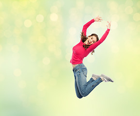 Image showing happy young woman jumping in air or dancing