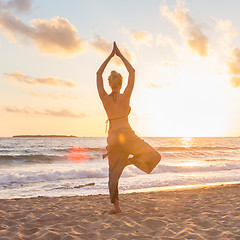 Image showing Woman practicing yoga on sea beach at sunset.