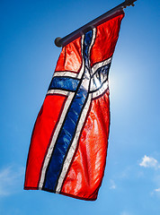 Image showing Norwegian flag up close, towards the sun on beautiful blue sky