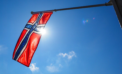 Image showing Norwegian flag up close, towards the sun on beautiful blue sky