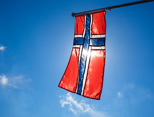 Image showing Norwegian flag up close, towards the sun on beautiful blue sky