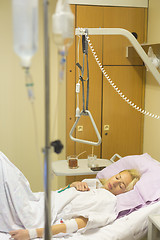 Image showing Bedridden female patient recovering after surgery in hospital care.