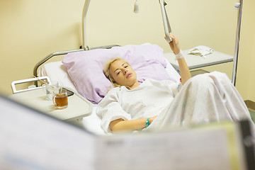 Image showing Bedridden female patient recovering after surgery in hospital care.