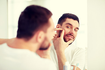 Image showing man squeezing pimple at bathroom mirror