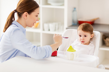 Image showing happy mother feeding baby with puree at home
