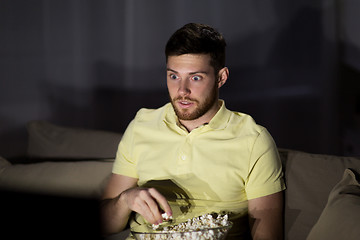 Image showing man watching tv and eating popcorn at night