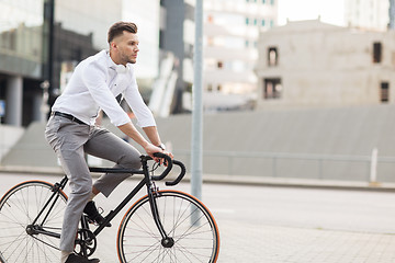 Image showing man with headphones riding bicycle on city street