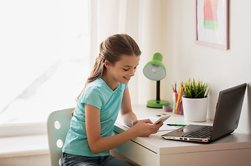 Image showing girl with laptop and smartphone texting at home