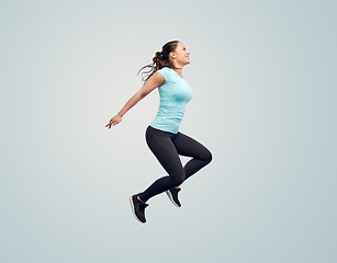 Image showing happy smiling sporty young woman jumping in air