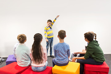 Image showing happy student boy showing something at white wall