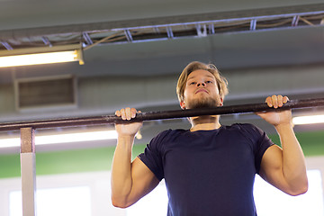 Image showing man exercising on bar and doing pull-ups in gym