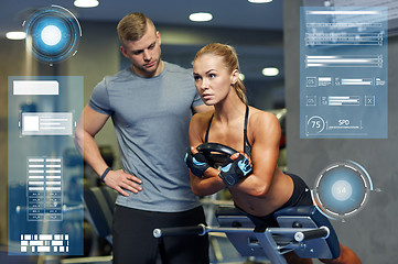 Image showing woman with personal trainer flexing muscles in gym