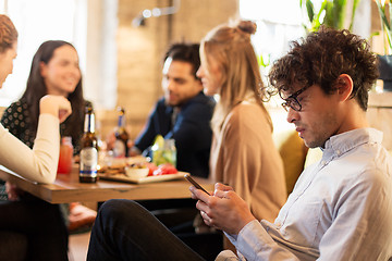 Image showing man with smartphone and friends at restaurant