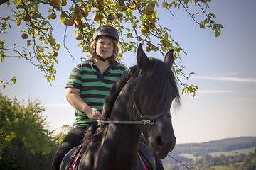 Image showing Beautiful young woman rides her black Horse 