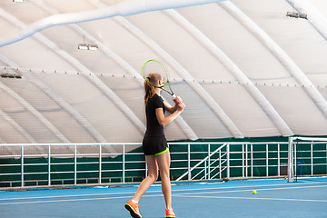 Image showing The young girl in a closed tennis court with ball