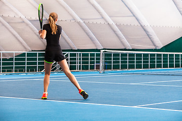 Image showing The young girl in a closed tennis court with ball
