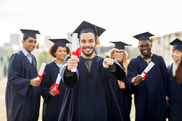 Image showing happy student with diploma pointing finger at you