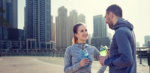 Image showing smiling couple with bottles of water in city