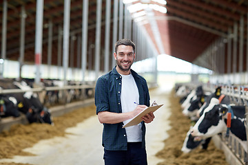 Image showing farmer with clipboard and cows in cowshed on farm