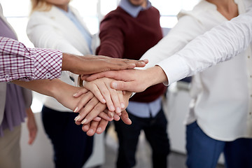 Image showing happy business team with hands on top at office