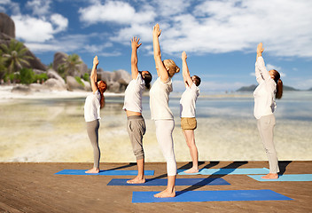Image showing group of people making yoga exercises over beach