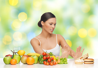 Image showing woman with fruits rejecting fast food on table