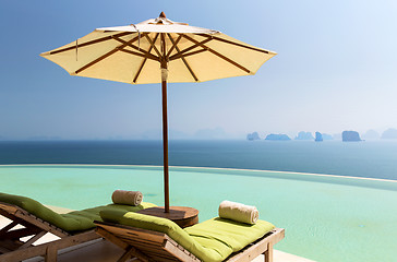 Image showing infinity pool with parasol and sun beds at ocean