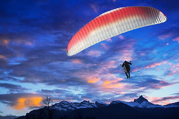 Image showing Paraglider flying over mountains in winter sunset