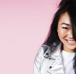 Image showing young pretty smiling asian korean girl wearing modern fashion clothers on pink background, lifestyle people concept 