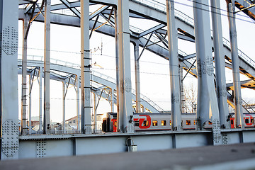 Image showing landscape with railway with trains, lot of steel rafters at sunset