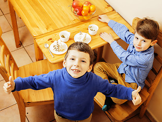 Image showing little cute boys eating dessert on wooden kitchen. home interior. smiling adorable friendship together forever friends, lifestyle people concept